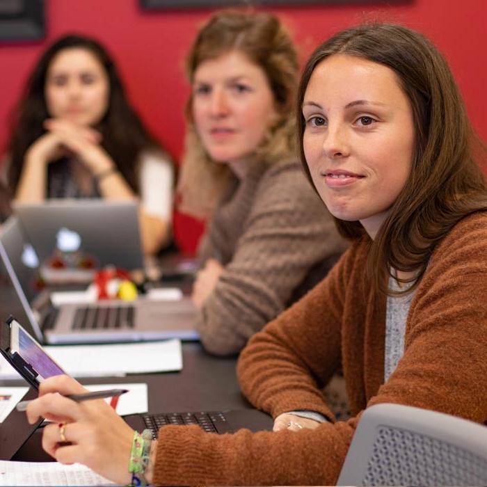 Three students in classroom listening to professor lecture